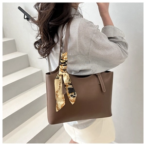 Detail of dark brown leather tote bag with elegant floral scarf handle on white steps