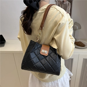 Sac bandoulière matelassé noir avec chaîne dorée et fermoir pivotant sur modèle