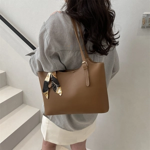 Brown leather tote bag with decorative floral scarf on a model for spring 2025 fashion