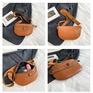 Detail view of brown PU leather waist bag with skull embossing and metal skull charm