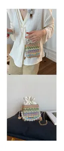 Detail of colorful woven straw bucket bag with pearl handle and metal chain strap