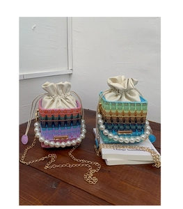 Detail of woven bucket bags with pearl handles and drawstring closure in gradient colors