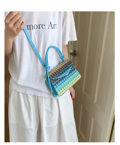 Detail of colorful gradient woven straw mini bag with vibrant blue cylindrical handle