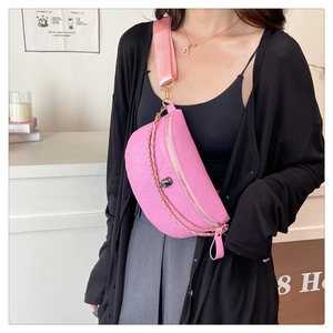 Detail of hot pink crossbody bag with skull embossing and gold chain on wide strap