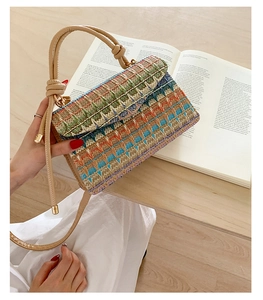 Detail of colorful wavy woven bag with knotted leather strap and golden metal buckle