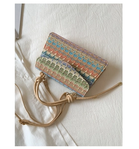 Detail of colorful woven straw handbag with geometric patterns and beige strap