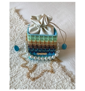 Detailed top view of striped straw bucket bag with pearl handle and golden chain strap