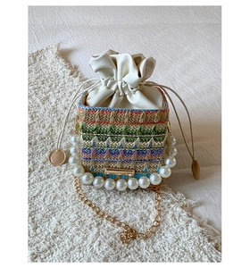 Detail of colorful woven drawstring bucket bag with large pearl handle and gold chain