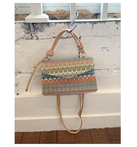 Detail of colorful bohemian woven bag featuring a zigzag pattern and khaki strap