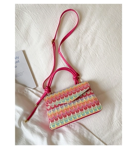 Detail of colorful woven straw bag with pink handle and vibrant geometric patterns