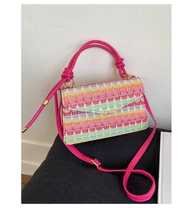 Close-up of a colorful woven crossbody bag with vibrant patterns and pink leather straps