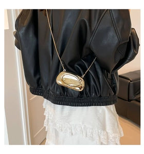 Detailed view of an oval gold acrylic evening bag with a luxury mirror finish and chain