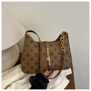 Detailed close-up of retro brown monogram shoulder bag with gold chain on white fabric