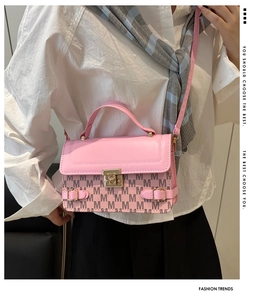 Detail of pink leather handbag with M-letter pattern and gold metal twist lock
