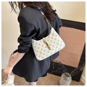 Detail view of cream-white crescent shoulder bag with monogram print and gold chain