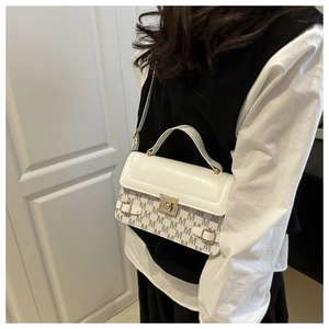 Detail shot of a vintage print handbag with metal clasp worn by a model in a lifestyle setting