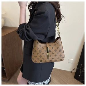 Detail of vintage brown monogram shoulder bag with gold chain and metal buckle closure