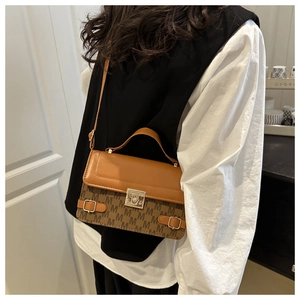 Detail of a vintage-style brown crossbody bag with M-letter prints and golden hardware