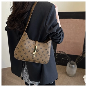 Chic brown leather crescent bag with logo pattern and gold buckle shown on a model