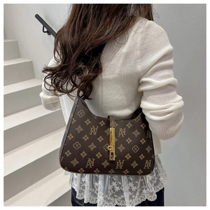 Detailed view of the brown monogram crossbody bag showing the gold metal clasp and pattern