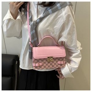 Detailed view of pink crossbody bag with M-pattern print and gold clasp on model