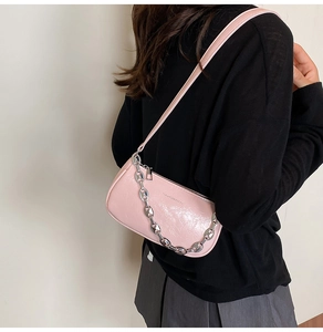 Dettaglio della borsa a spalla rosa lucida a pieghe con catena d'argento e tracolla