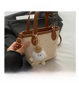 Gros plan sur un mini sac seau crème avec imprimé dessin animé et poignées en cuir brun
