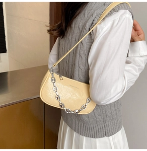 Dettaglio borsa sottobraccio arricciata giallo chiaro con catena argento e zip