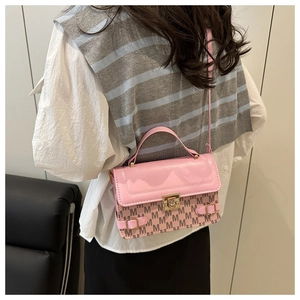 Pink crossbody bag with M-pattern print and gold clasp shown on a model indoors