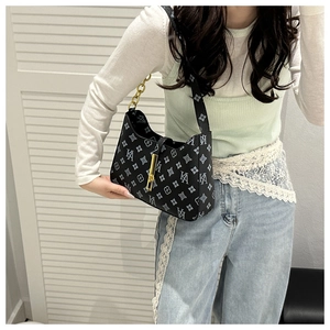 Detail of black monogram shoulder bag with gold hardware and chain strap on a model