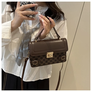 Detail view of a vintage brown handbag with M-pattern print and gold clasp closure
