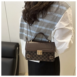 Detail of vintage patterned crossbody bag with metallic lock and slim adjustable strap