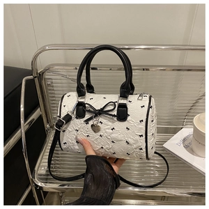 Close-up of seersucker Boston bag featuring black bow embroidery and heart metal charm