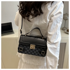 Detail of cross-body handbag with M-pattern print and gold clasp on a model