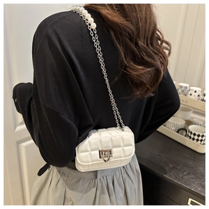 Detail of white quilted crossbody bag featuring elegant pearl and metal chain straps