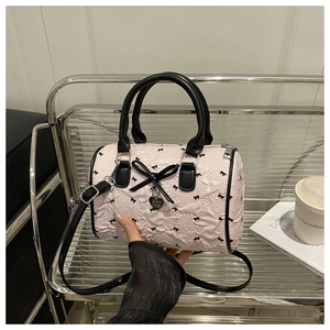 Detail of seersucker Boston bag with black bow patterns and heart-shaped metal pendant