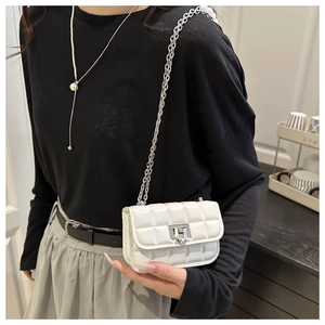 Detail of white quilted crossbody bag with silver chain strap and twist-lock closure