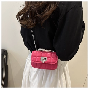 Detail of fuchsia quilted mini bag featuring large faux pearl handle and silver chain