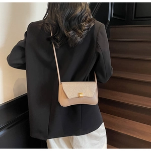 Détail du rabat pailleté et du fermoir doré sur le sac bandoulière en cuir beige