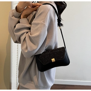 Détail du sac sous le bras noir avec rabat à paillettes et fermoir en métal doré sur mannequin