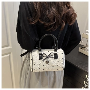 Détail du sac Boston en jacquard blanc avec broderie nœuds et pendentif cœur