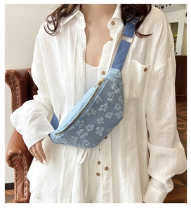 Detail of light blue floral jacquard chest bag with gold zipper and wide nylon strap