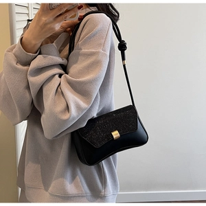 Détail du sac à bandoulière noir avec rabat scintillant et boucle en métal doré