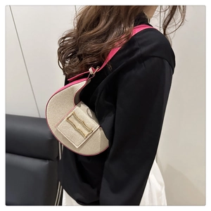 Vue détaillée du sac croissant en toile beige avec bordure en cuir rose et boucle dorée