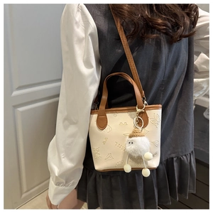 Détail du sac seau crème avec motifs papillons en relief et charme en peluche