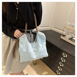 Detail of light blue denim tote bag with brown braided rope handle and metal buckle