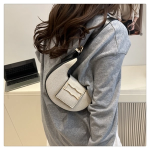 Détail du sac croissant beige avec bordures noires et boucle dorée moderne en vague