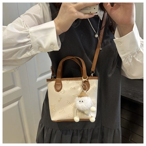 Mini sac seau bandoulière avec imprimés papillon et pompon porté par un mannequin
