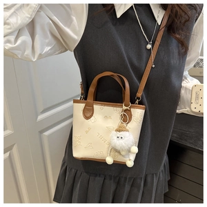 Détail du mini sac seau crème avec motifs embossés mignons et pendentif en peluche