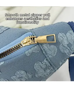 Close-up of a smooth golden metal zipper pull on a blue embroidered floral saddle bag